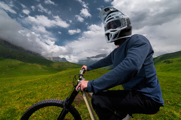 Back view wide angle of mountain bike and man in mountains against mountain range and hills with...