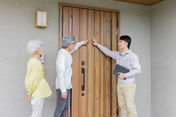 住宅の前で説明する男性作業員とシニア夫婦