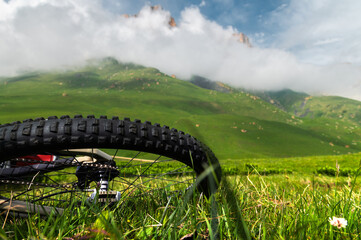 Close-up of rear wheel of mountain bike against rocky mountains in clouds. Copy space
