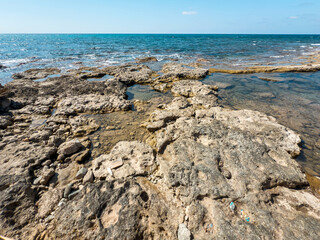 Natural rocky beach coastline with turquoise sea in summer sunlight, peaceful Mediterranean holiday...