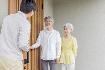 住宅の前で説明する男性作業員とシニア夫婦