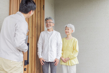 住宅の前で説明する男性作業員とシニア夫婦