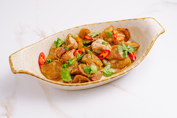 Stir-fried pork with crispy potatoes, red chili slices, and fresh cilantro served in a rustic...