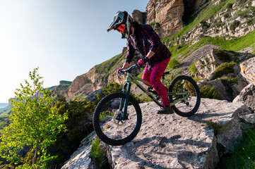 Cyclist in red riding a bike on a rocky trail off-road. Extreme sports and enduro bike concept