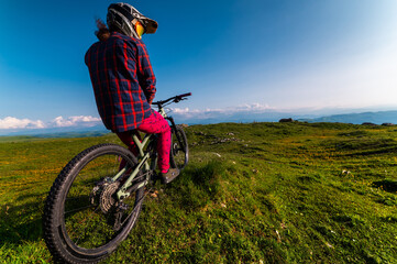 Back view wide angle of mountain bike and man in mountains against mountain range and hills with...