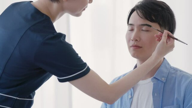美容部員に眉毛のメイクをしてもらう男性