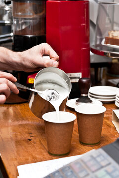 barista pouring milk into takeaway coffee cups