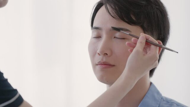 美容部員に眉毛のメイクをしてもらう男性