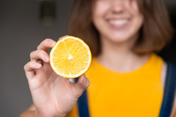 Woman smiling, playful lemon portrait. Portrait of gorgeous lady holding half lemon in hands, room...