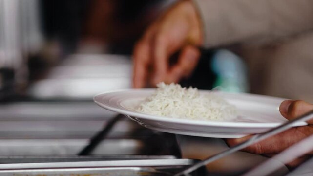 Kunde serviert sich selbst am Buffet eines indischen Restaurants einen gro&szlig;en Teller voll Essen