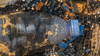 Oil pollution of sea and coast. Floating objects (flotsam, bottle) are covered with fuel oil and...