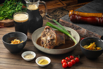Roasted pork knuckle with sauces cabbage and potatoes on wooden table