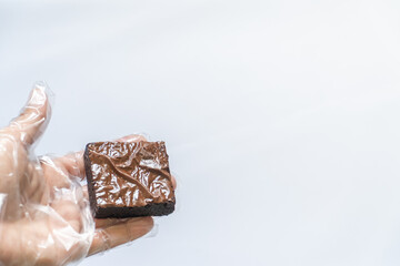 Single Fuggy Brownie Held by Gloved Hand, Ample White Space