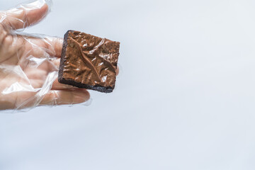 Hand in Clear Glove Presenting Single Brownie, White Background