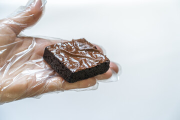 Side View of Gloved Hand Presenting Single Brownie