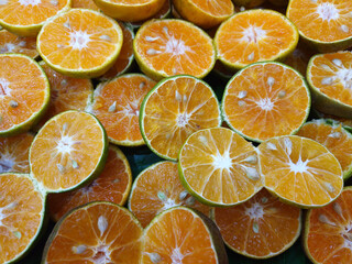 Multiple halved Green Tangerines, also known as King Mandarins or Terracotta Oranges, seeds visible top view background