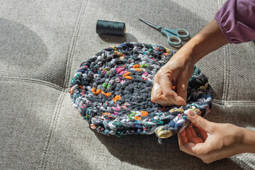 Hand sewing colorful upcycled fabric rug