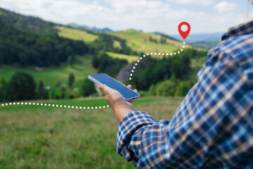 A close-up of a hiker's hands holding a smartphone, tracking a digital route marked by a dotted...