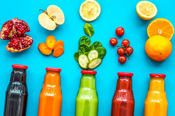 bottles with fresh carrot, tomato, apple, cucumber, lemon, pomegranate juices on blue background...