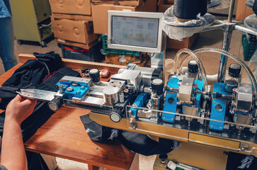 Textile industry, automatic knitting of socks. Machine for sewing tops of socks. Hands of a worker.