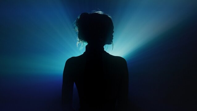 Silhouette of woman with radiating blue light beams