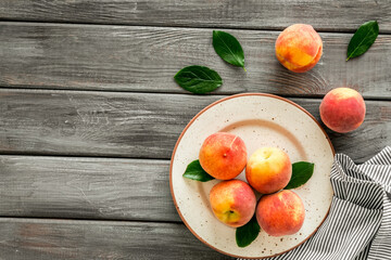 Summer lunch. Red peaches on wooden background with tablecloth and leaves top-down copy space