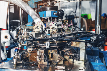 Circular knitting machine on blurred background. Textile industry, automatic knitting of socks.