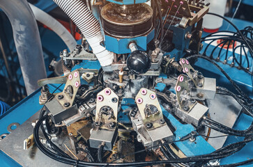 Circular knitting machine on blurred background. Textile industry, automatic knitting of socks.