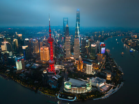 Shanghai, China - 21 June 2025: Aerial view of the illuminated Oriental Pearl Tower and towering skyscrapers piercing through the twilight sky along the Huangpu River.
