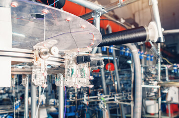 Thread tensioners located on spools on machines. Industrial enterprise for the production of socks.