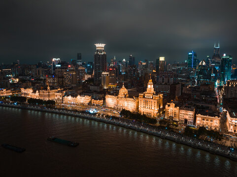 Shanghai, China - 21 June 2025: Aerial view of Shanghai's glowing Bund and Pudong skyline shimmer over the dark Huangpu River, a symphony of light and shadow.