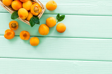 Collect apricots, green wooden background top view copy space, pattern with leaves