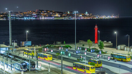 Fototapeta premium Aerial night timelapse of Cacilhas bus and railway station with the Tagus River, Lisbon glowing skyline