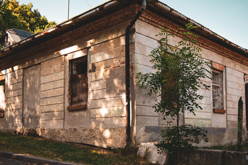  The corner view of an old, weathered house showing its distressed facade with peeling, faded...