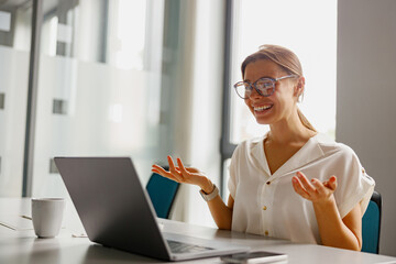 A cheerful woman actively participates in a virtual business meeting, showing her professionalism...