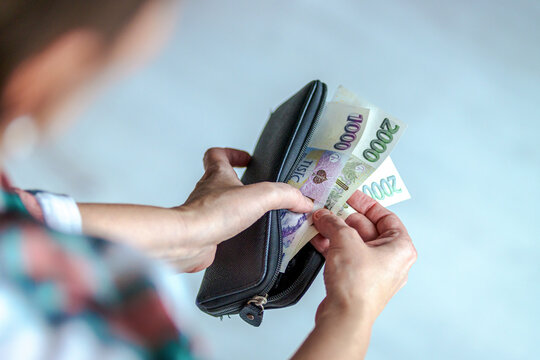 Woman taking out Czech banknotes from a wallet. Concept of finance, cash payment, personal budget, or economic situation in the Czech Republic.