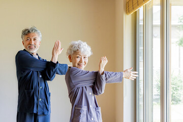 パジャマで柔軟体操をするシニアカップル