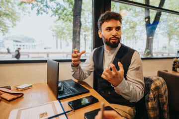 A young businessman passionately discussing ideas with his team during a meeting in a cafe. The...