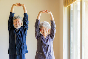 パジャマで柔軟体操をするシニアカップル