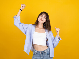Winner woman concept image, portrait of young happy cool brunette caucasian woman wear white top shirt casual clothes standing over isolated yellow background raise up hands fists, dance have fun.