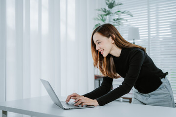 Smile Young business Asian woman freelancer is working her job on a laptop computer in a modern...