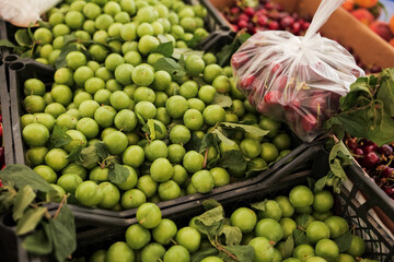 Fresh green plums and cherries on display at a vibrant local market stall