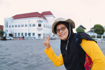 Smiling Woman Giving Victory Sign in Front of Historic City Building