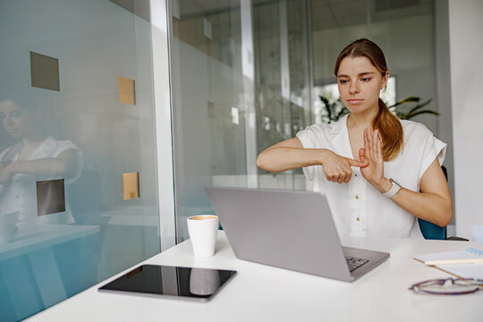 A young woman is actively engaging in virtual communication while working in a contemporary workspace. - Powered by Adobe