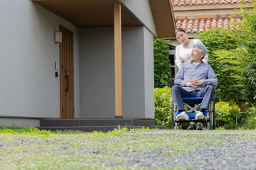 庭で車椅子に乗るシニア男性と介護士