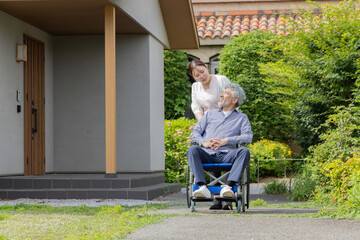 庭で車椅子に乗るシニア男性と介護士