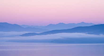 Fototapeta premium Mountain range at dawn with fog and pastel colored sky in a scenic landscape