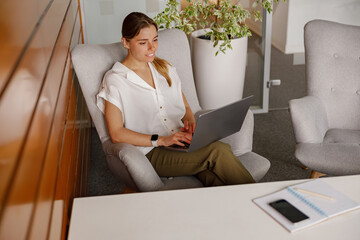 In a stylish office designed for productivity, a dedicated businesswoman diligently works on her...