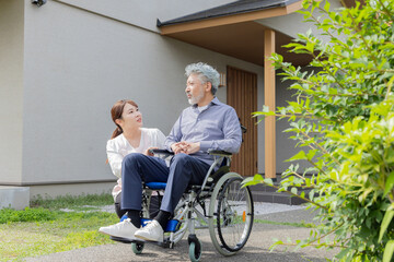 庭で車椅子に乗るシニア男性と介護士