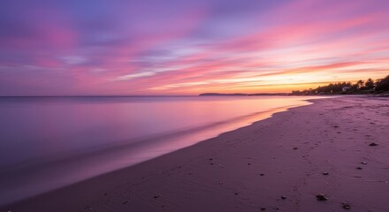 Obraz premium Calm beach scene at sunset with pink and purple hues in the sky and water